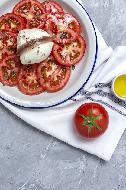 Gesunder hausgemachter tomatensalat mit mozzarella, sardellen und oregano