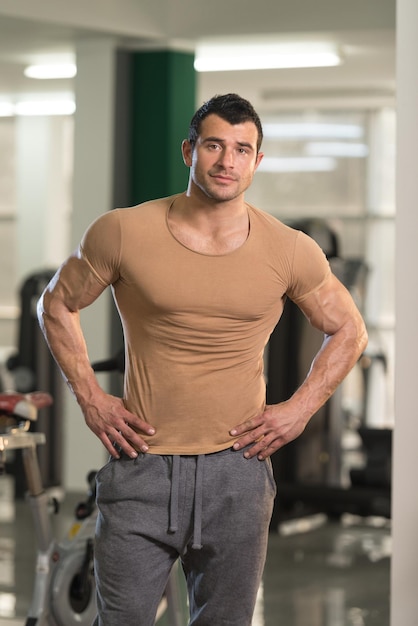 Gesunder junger Mann im braunen T-Shirt, der stark steht und Muskeln biegt Muskulöser athletischer Bodybuilder Fitness Model posiert nach Übungen