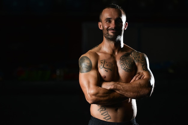 Gesunder junger Tattoo-Mann, der stark in der Turnhalle steht und Muskeln anspannt Muskulöser athletischer Bodybuilder Fitness Model posiert nach Übungen