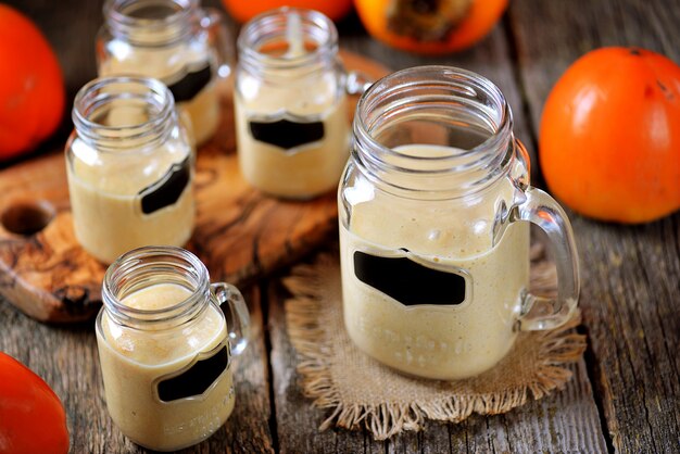 Gesunder Kakis-Smoothie mit Banane und Joghurt auf hölzernem Hintergrund