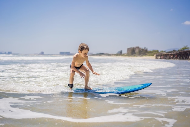 Gesunder kleiner Junge, der lernt, im Meer oder Ozean zu surfen