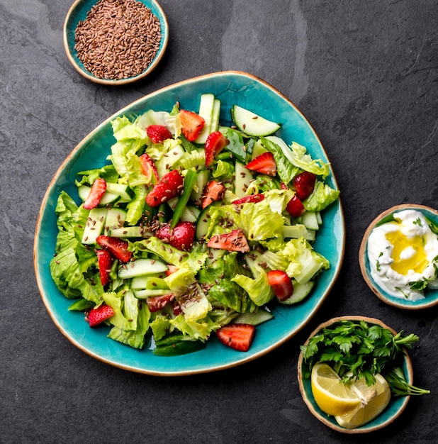 Gesunder Kopfsalaterdbeersalat mit Leinensamen auf Draufsicht der blauen Platte