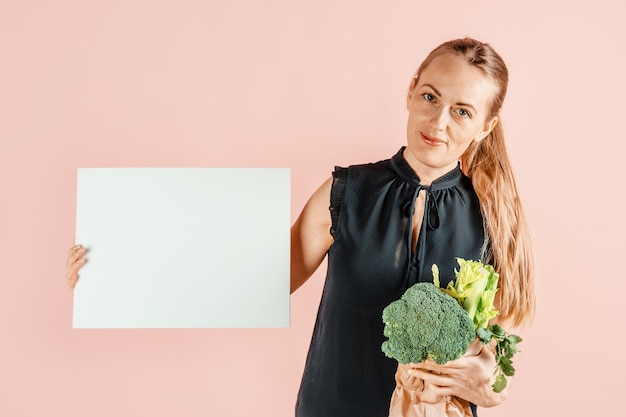 Gesunder Lebensstil. Mädchen hält Brokkoli und grünes Gemüse in ihren Händen, rosa Wand. Diät und richtige Ernährung. .