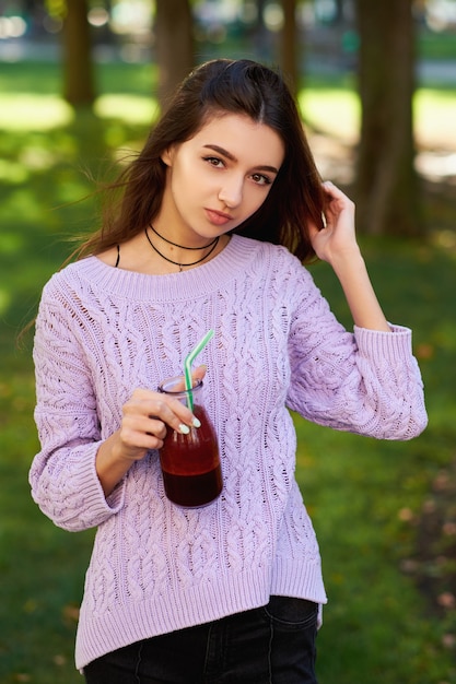 Gesunder Lebensstil. Nette junge Frau mit frischem Smoothieglas der roten Rübe, auf grünem Naturhintergrund.