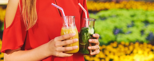 Gesunder Lebensstil. Unerkennbare junge Frau mit Frucht-Detox-Smoothie im Sommer, auf grünem Naturhintergrund