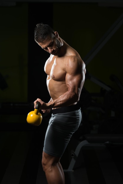 Gesunder Mann, der mit Kettle Bell trainiert und Muskeln anspannt Muskulöser athletischer Bodybuilder Fitness Model Übungen