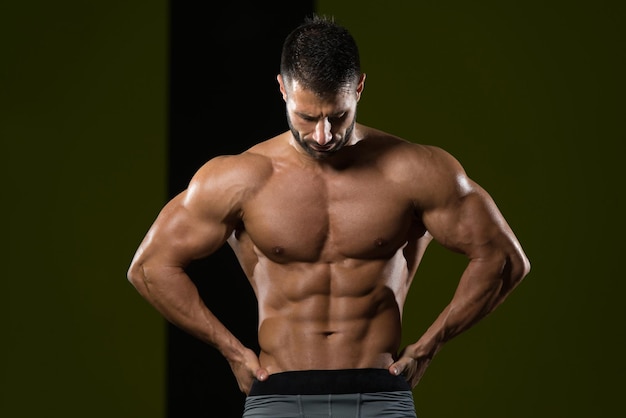 Gesunder Mann, der stark in der Turnhalle steht und Muskeln anspannt Muskulöser athletischer Bodybuilder-Eignungsmodell, der nach Übungen aufwirft