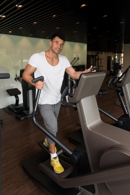 Gesunder Mann macht Aerobic Elliptical Walker im Fitnessstudio