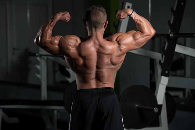 Gesunder reifer Mann, der stark in der Turnhalle steht und Muskeln muskulöser athletischer Bodybuilder-Eignungs-Mann aufwirft, der nach Übungen aufwirft