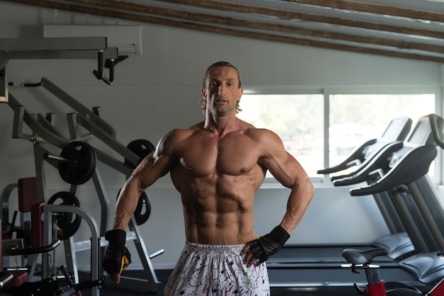 Gesunder, reifer Tattoo-Mann, der stark im Fitnessstudio steht und Muskeln muskulöser, athletischer Bodybuilder-Eignungsmodell posiert, der nach Übungen posiert