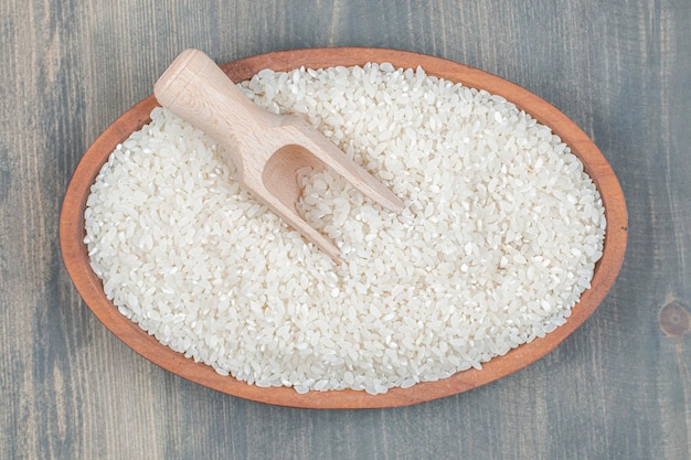 Gesunder roher Reis mit Holzlöffel auf einem Holztisch