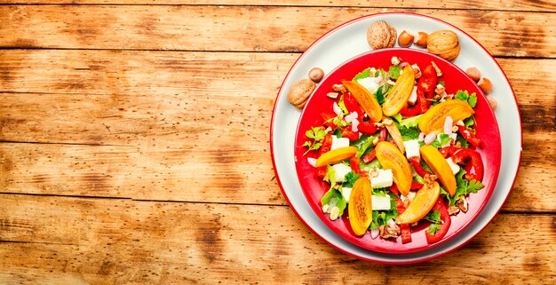 Gesunder Salat mit Kaki und Feta-Käse. Saisonaler Salat auf Holztisch. Platz für Text