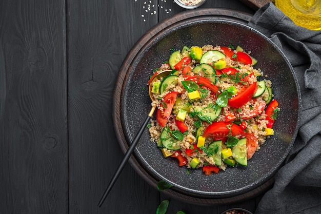 Gesunder Salat mit Quinoa-Gemüse und frischen Kräutern auf schwarzem Hintergrund Vegetarischer Salat