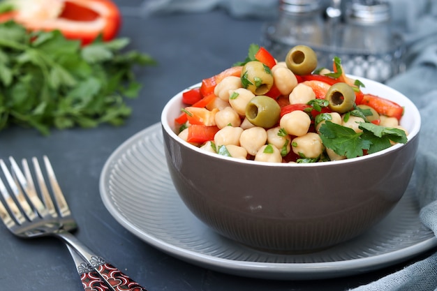 Gesunder Salat von Kichererbsen, grünen Oliven, Pfeffer und Petersilie, auf Dunkelheit