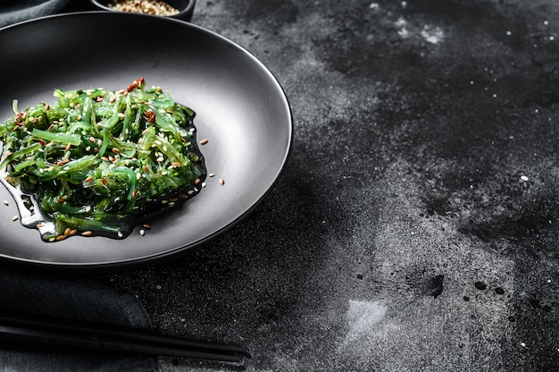 Gesunder Seetang-Chuka-Salat mit Gemüse. Schwarzer Hintergrund. Draufsicht. Speicherplatz kopieren