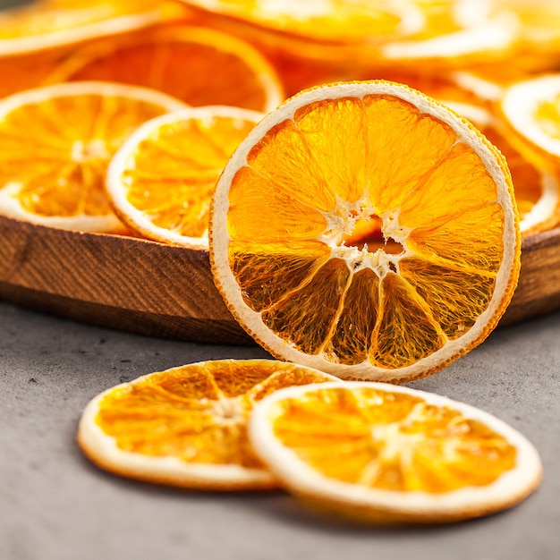 Gesunder Snack. Getrocknete Orangenscheiben Nahaufnahme auf einem Holzteller.