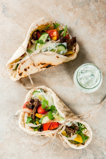 Gesunder Snack, Mittagessen. Traditionelle griechische Sandwichgyros - Tortillas, Fladenbrot mit einer Füllung aus Gemüse, Rindfleisch und Sauce Tzatziki