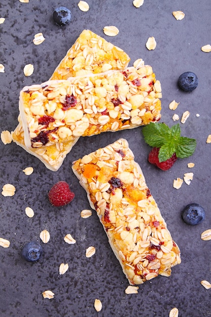 Gesunder Snack, Müsliriegel mit Rosinen und getrocknete Beeren auf einem schwarzen Hintergrund