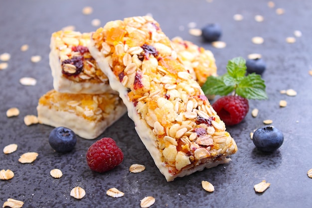 Gesunder Snack, Müsliriegel mit Rosinen und getrocknete Beeren auf einem schwarzen Hintergrund