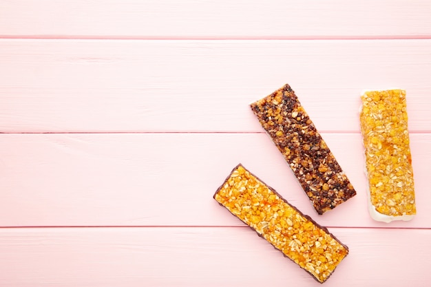 Gesunder Snack, Müsliriegel mit Rosinen und getrockneten Beeren auf einem rosa Hintergrund