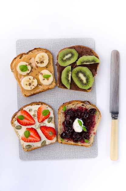 Gesunder Snack-Toast mit Fruchtfüllung und Samen auf einem Brett und einem Messer auf weißem Hintergrund