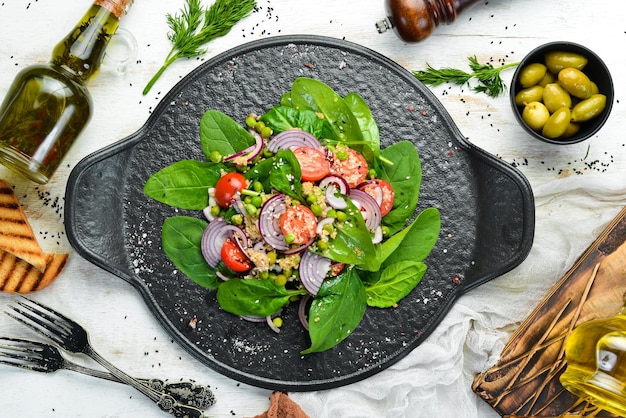 Gesunder veganer Salat aus Spinat, Quinoa, Tomaten und Gemüse. Ansicht von oben. Rustikaler Stil.