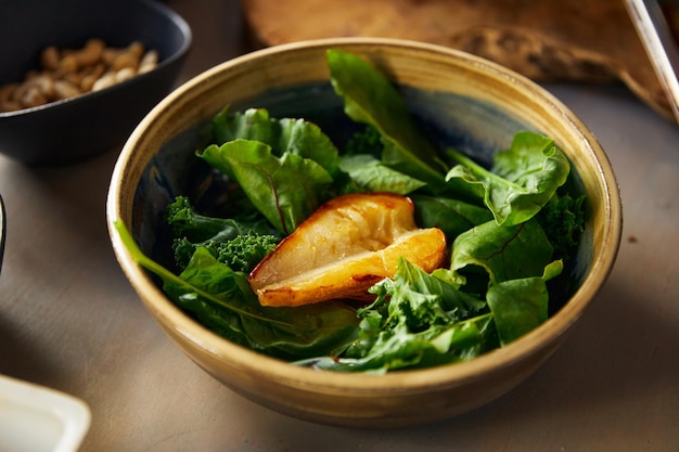 Gesunder veganer Salat mit gebackener Birnenhälfte in Schüssel auf dem Tisch