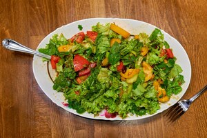 Gesunder vitaminsalat aus grünen blättern und verschiedenem gemüse in einem großen weißen teller