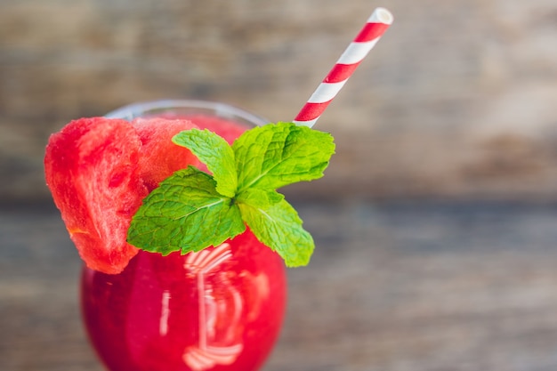 Gesunder Wassermelonen-Smoothie mit Minze und gestreiften Strohhalmen auf einem Holztisch