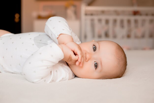 Gesundes Baby lächelt liegend auf Bett zu Hause