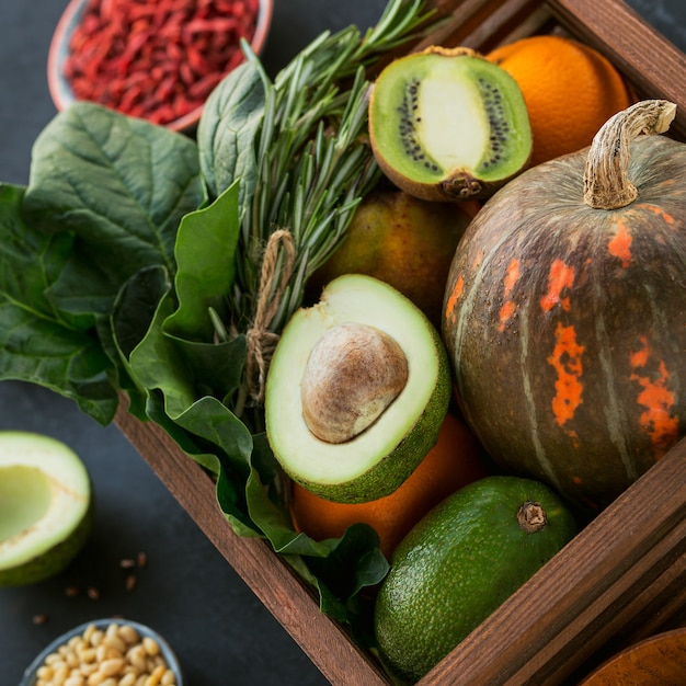 Gesundes Bio-Lebensmittel für Landwirte in Holzkiste: Obst, Gemüse, Samen, Superfood, Blattgemüse auf schwarzem Hintergrund. Auswahlkonzept für sauberes Essen