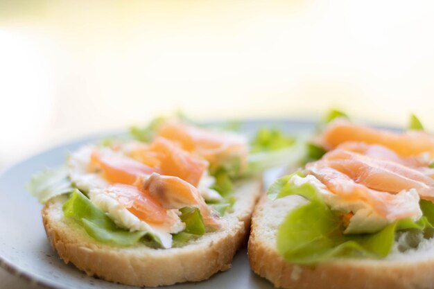 Gesundes Bio-Sandwich mit Lachs und Bagel-Frischkäse und wilder Rucola auf Holzbrett