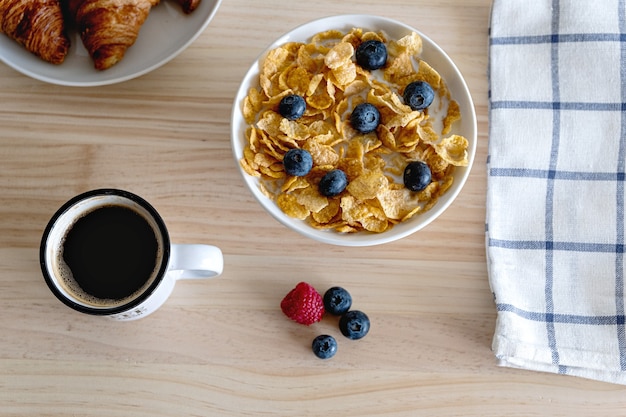 Gesundes Breaskfast-Konzept mit roten Früchten des Kaffeejoghurts und Croissant auf Woodden Tisch