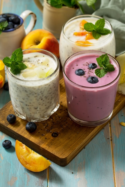 Gesundes Chia-Set Pudding in einem Glas mit Blaubeere mit Melone und Pfirsich auf Holzküchentisch