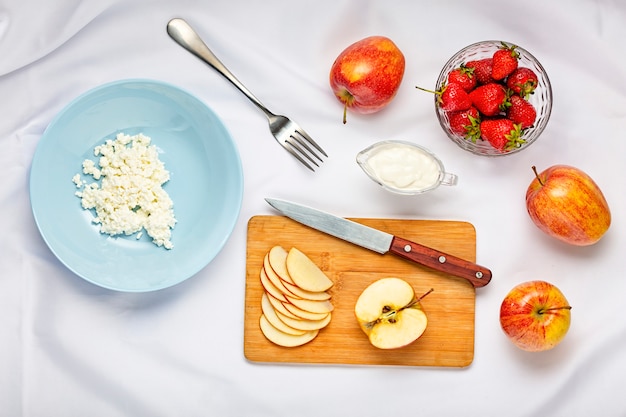 Gesundes Dessert mit Hüttenkäse und Erdbeeren in der blauen Platte auf einer weißen Tischdecke
