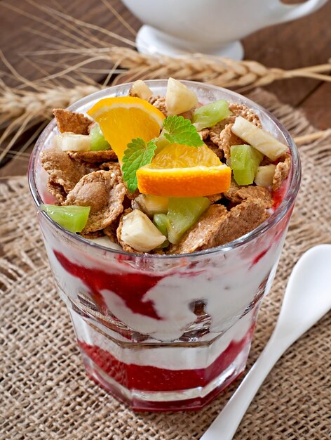 Gesundes Dessert mit Muesli und Obst in einer Glasschüssel auf dem Tisch