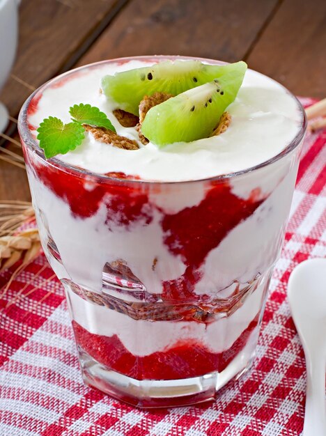 Foto gesundes dessert mit muesli und obst in einer glasschüssel auf dem tisch