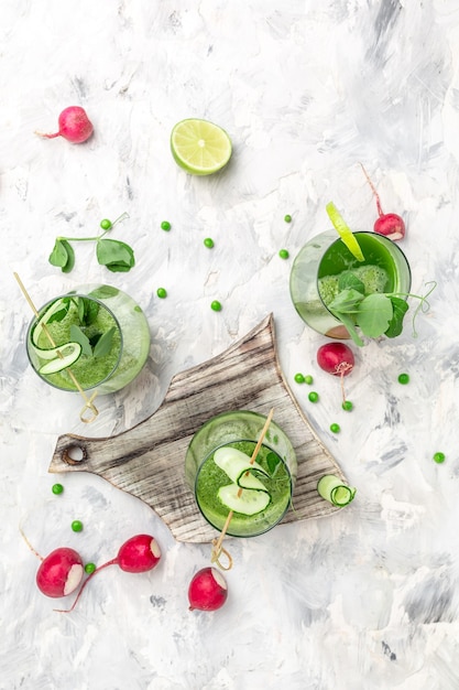 Gesundes Detox-Getränk Gesunder grüner Smoothie mit frischen Erbsen, Gurken, Spinat und Limette, vertikales Bild.