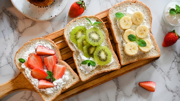 Gesundes Diät-Frühstücksset mit Erdbeer-Kiwi- und Bananen-Toppings auf Hüttenkäse und Toast