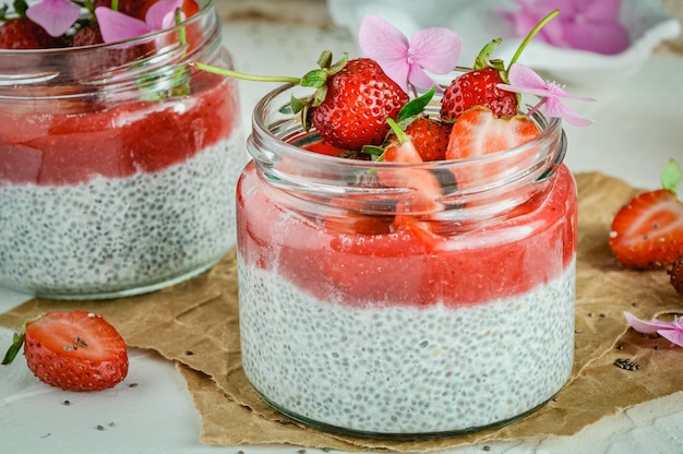 Gesundes Erdbeerfruchtdessert mit Milch und Chiasamen im Glas auf hellem Hintergrund