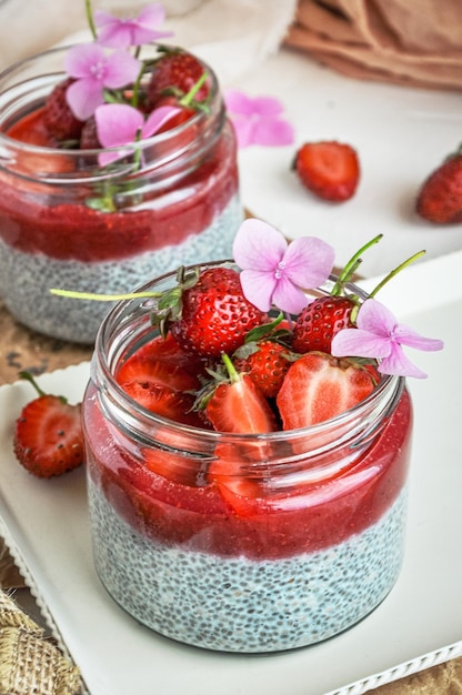 Gesundes Erdbeerfruchtdessert mit Milch und Chiasamen im Glas auf hellem Hintergrund