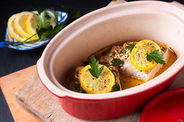 Foto gesundes ernährungskonzept hausgemachte zitronen-knoblauch-butter gebackener kabeljau auf schwarzem hintergrund mit kopierraum