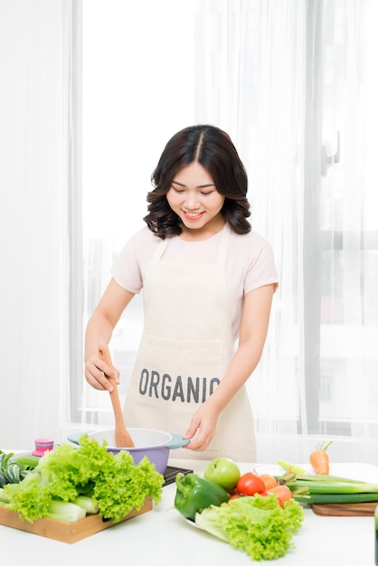 Gesundes Essen. Asiatische Frau kocht in der Küche mit Holzlöffel