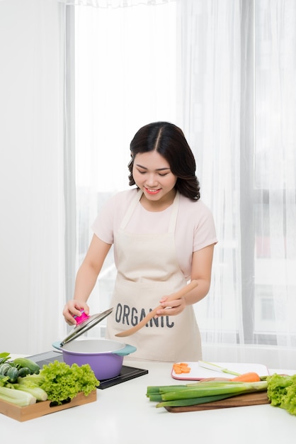 Gesundes Essen. Asiatische Frau kocht in der Küche mit Holzlöffel