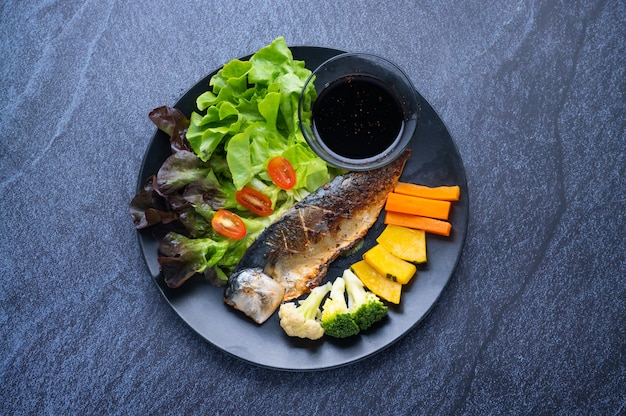 Gesundes Essen bestehend aus gegrilltem Fisch, verschiedenen Gemüsesorten, Kräutern und japanischer Sauce