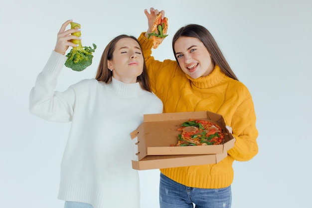 Gesundes Essen. Eine Frau hält eine Pizza und die andere einen Brokkoli