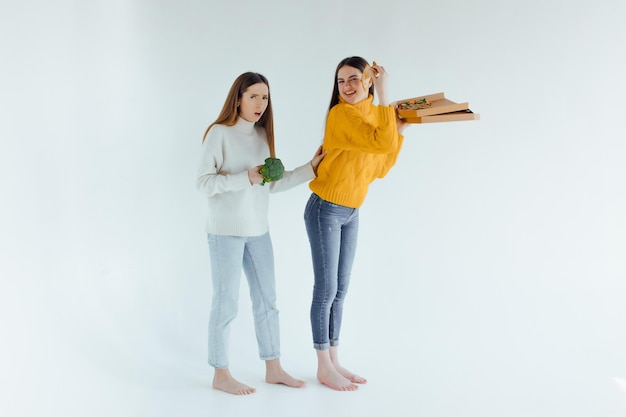 Gesundes Essen. Eine Frau hält eine Pizza und die andere einen Brokkoli