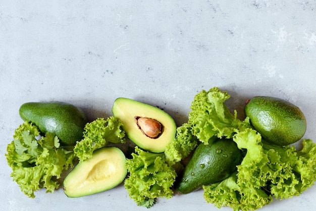 Gesundes Essen. Eine halbe reife Avocado mit Samen und Salat auf einem Teller an einer grauen Wand.