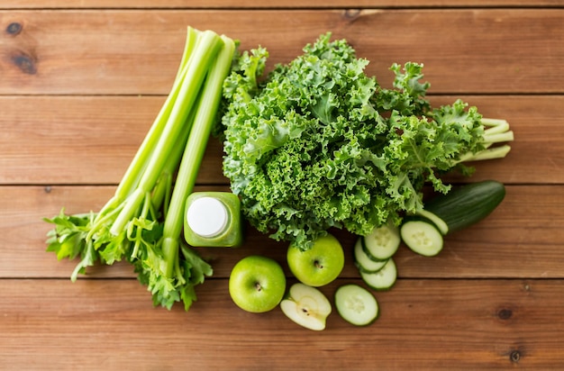 Gesundes Essen, Essen, Diät und vegetarisches Konzept - Nahaufnahme der Flasche mit grünem Saft, Obst und Gemüse auf Holztisch