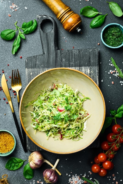 Gesundes Essen Frischer Kohlsalat, Radieschen mit Olivenöl auf einem Teller Restaurant serviert Nahaufnahme auf dunklem Steinhintergrund